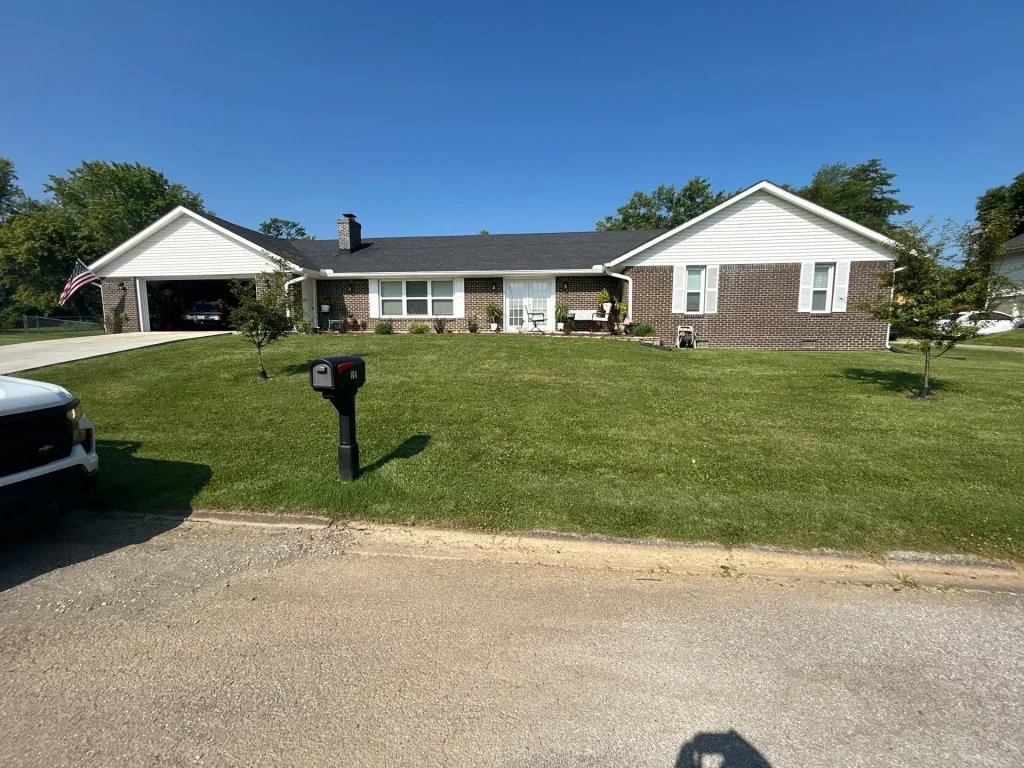 A single-story brick home in Richmond, KY with a new black shingle roof installed by AIC Roofing & Construction.