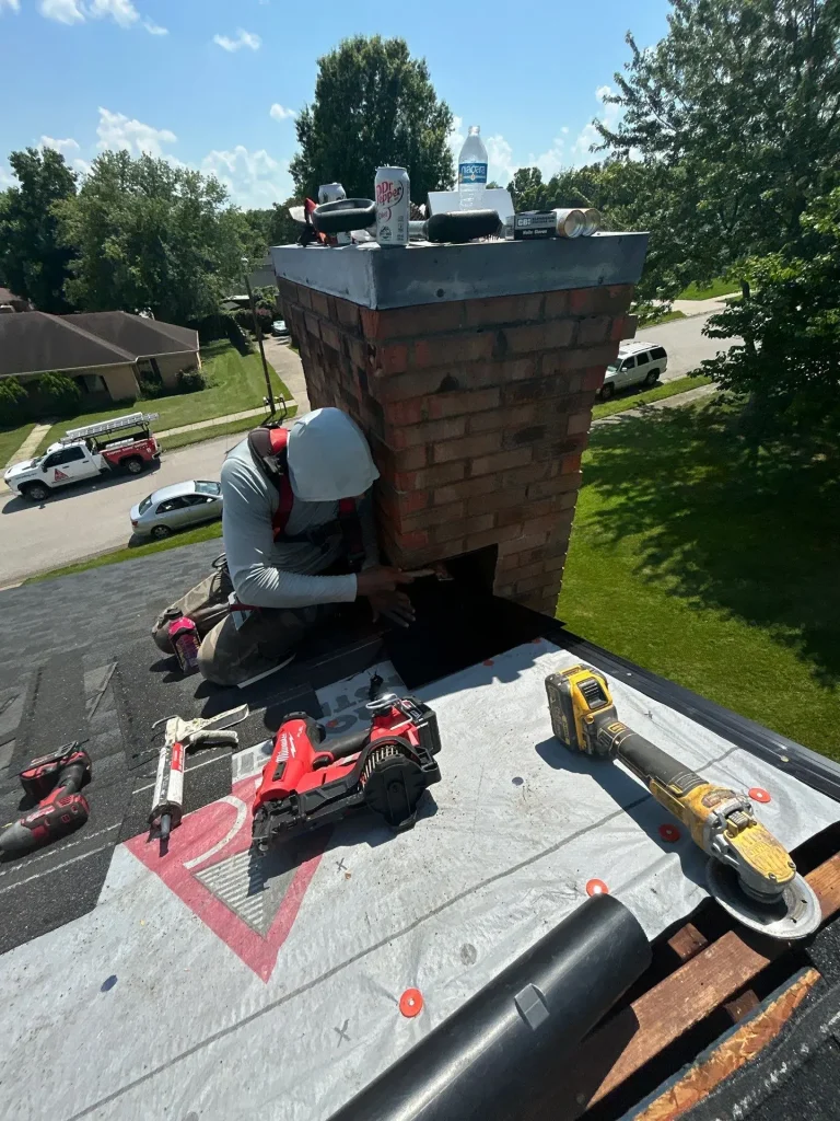 A roofer from AIC Roofing repairs flashing around a brick chimney during a roof repair in Richmond, KY.