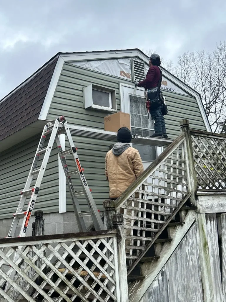 AIC Roofing crew installs new siding on the upper level of a Richmond, KY home using ladders and tools.