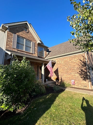 Brick Lexington, KY home with a new roof installed by AIC Roofing and an American flag displayed by the front porch.