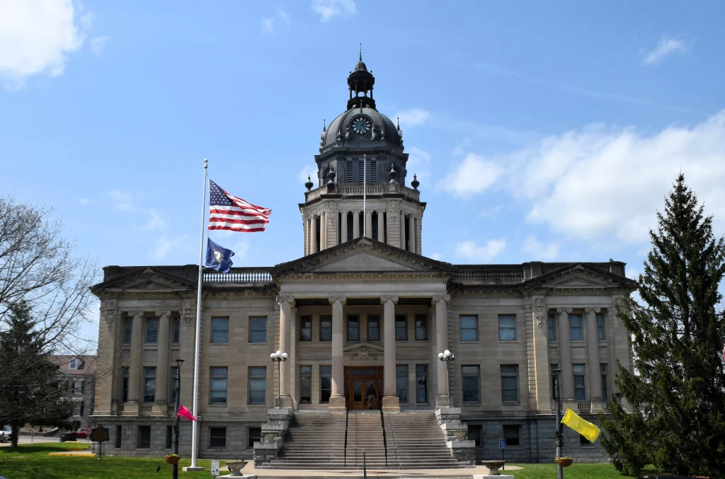 Neoclassical courthouse with a large dome and American flag in front.