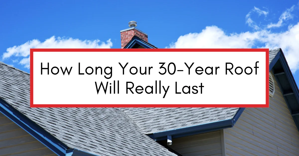 Close-up of a residential roof under a bright blue sky, featuring asphalt shingles and a chimney, symbolizing durability and lifespan of roofing systems.