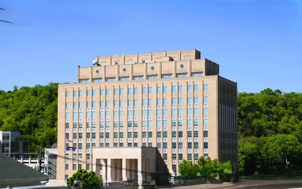 Tall beige government building in Frankfort, Kentucky, surrounded by trees and set against a clear blue sky
