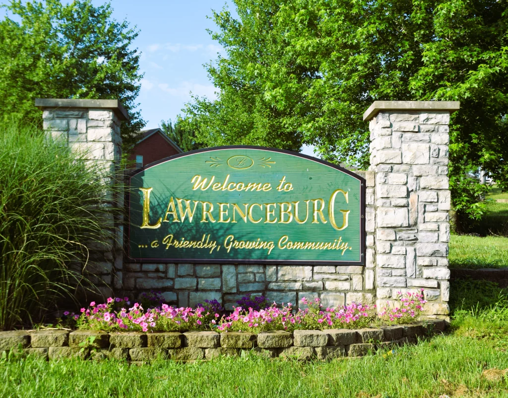 Welcome sign at the entrance to Lawrenceburg, KY surrounded by greenery and flowers