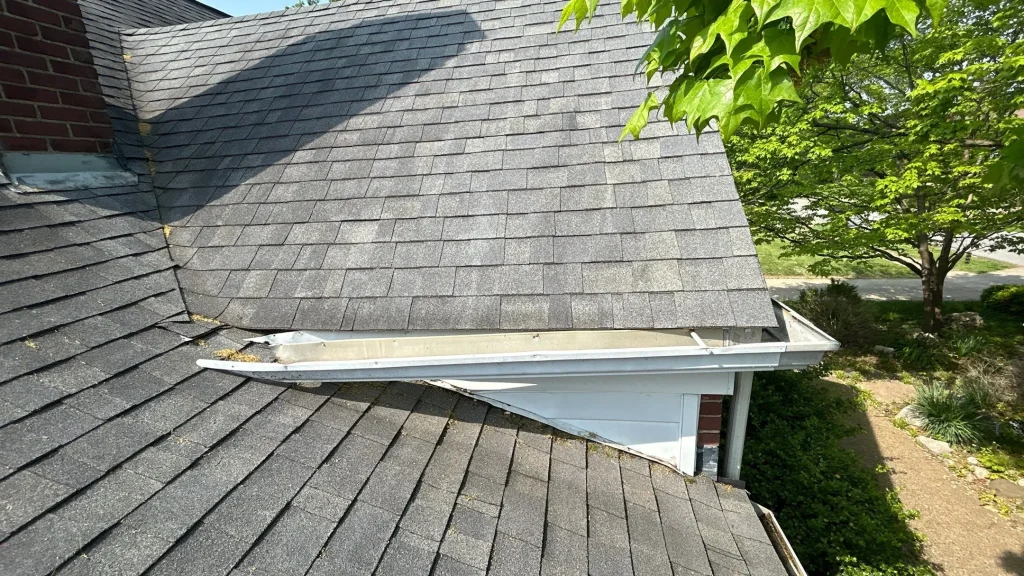 Broken Gutter with Debris on Louisville Home Damaged and sagging gutter with debris buildup on a Louisville roof