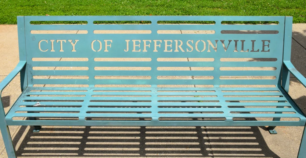 Teal metal bench with “City of Jeffersonville” cut into the backrest