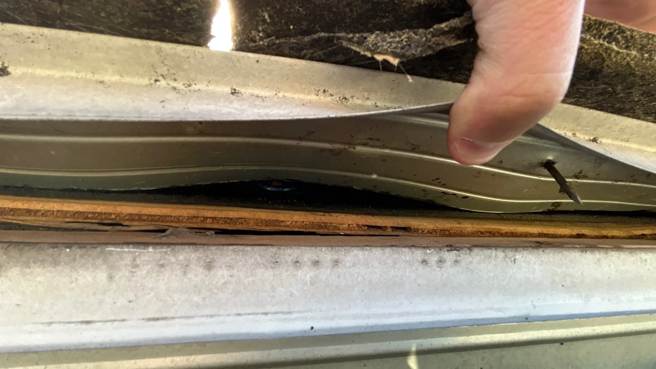 Close-up of a deteriorating gutter with loose metal and exposed wood on a Louisville building