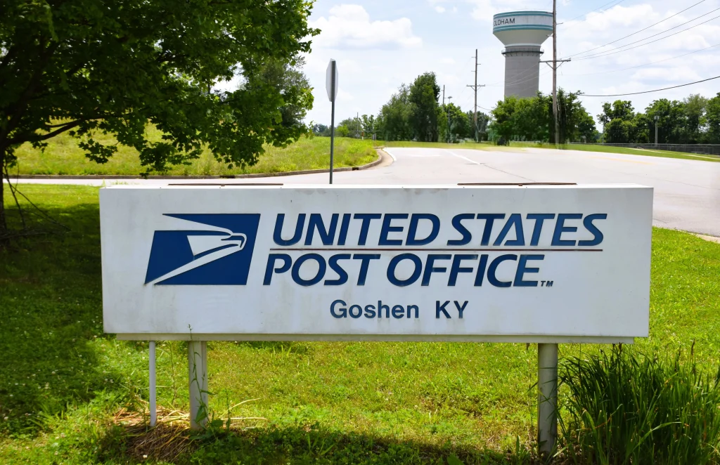 United States Post Office sign in Goshen Kentucky with Oldham County water tower in the background