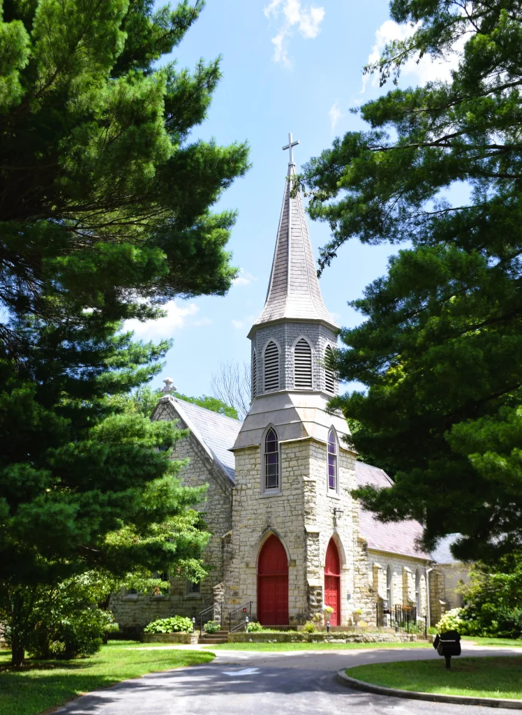 Stone church in Pewee Valley Kentucky with slate roof surrounded by pine trees