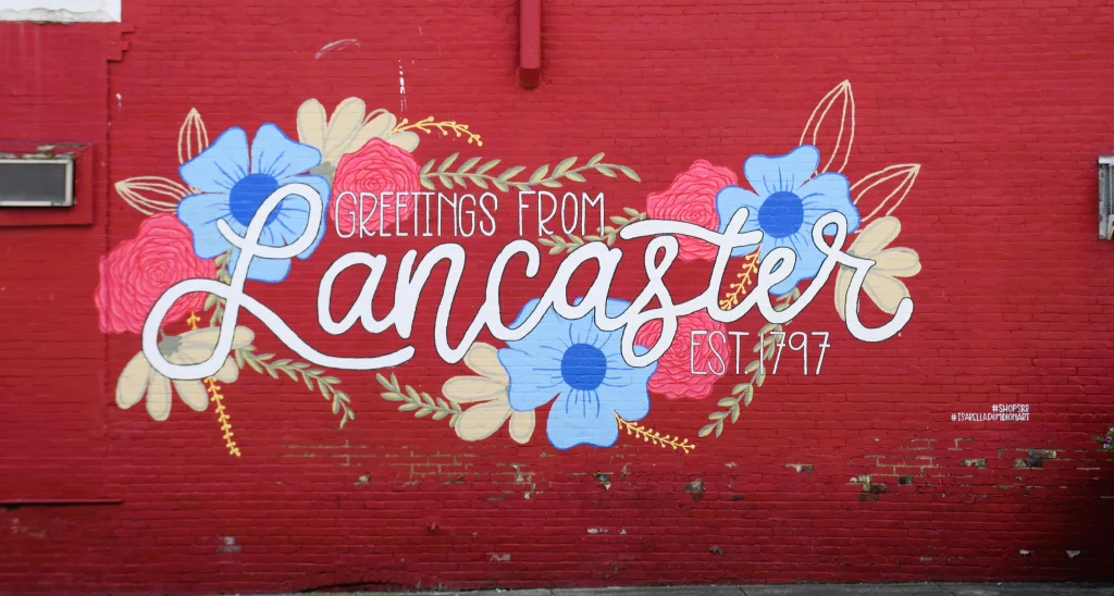Bright mural reading "Greetings from Lancaster Est. 1797" with floral designs