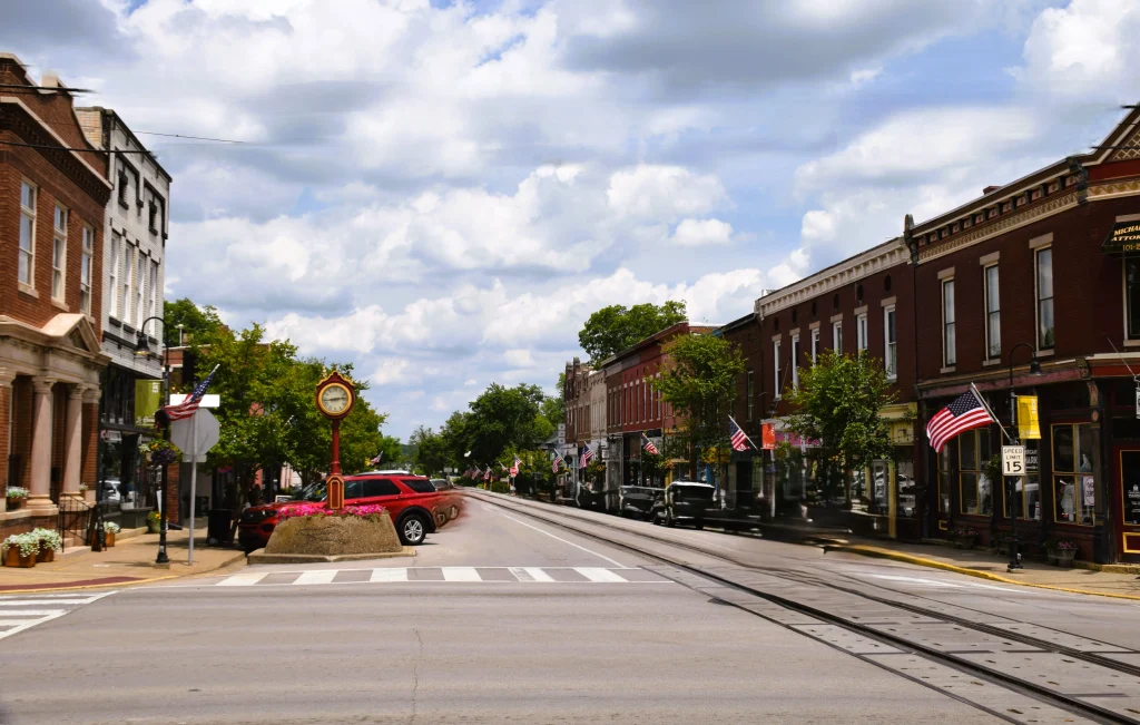 Small town street scene with historic shops, a red street clock, and American flags in La Grange, KY