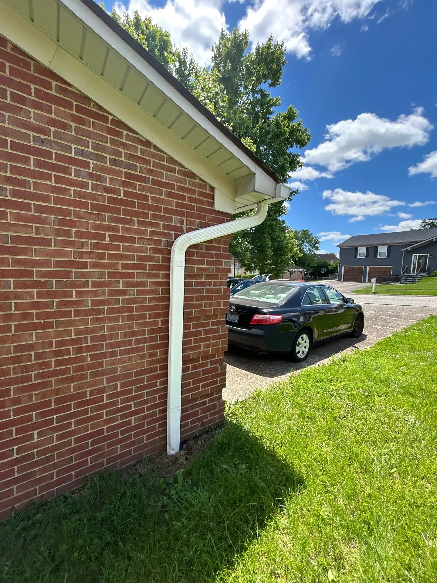 New white aluminum gutter and downspout installed on a red brick home in Richmond, KY by AIC Roofing & Construction