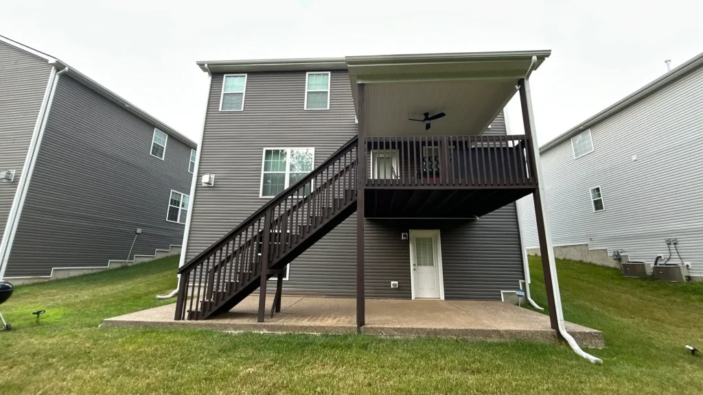 Rear view of a Louisville home with newly installed dark vinyl siding and a covered back deck.