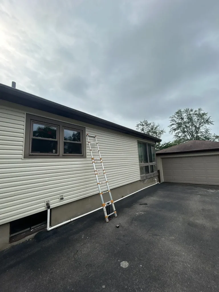 Freshly installed vinyl siding on a Louisville home with ladder leaning against the wall