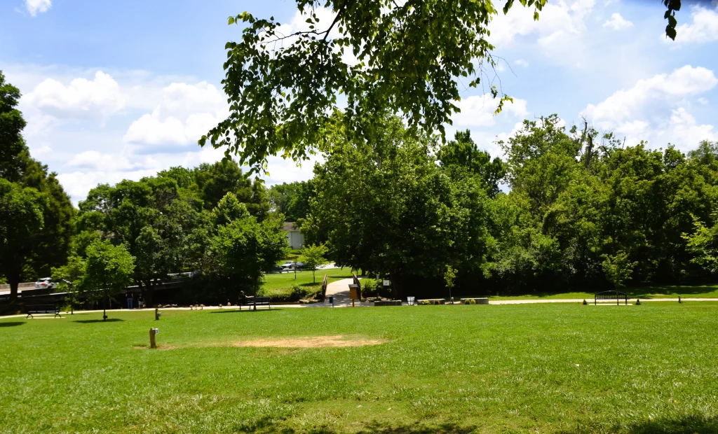 Grassy field and walking bridge in Brown Park near residential roofing in St. Matthews