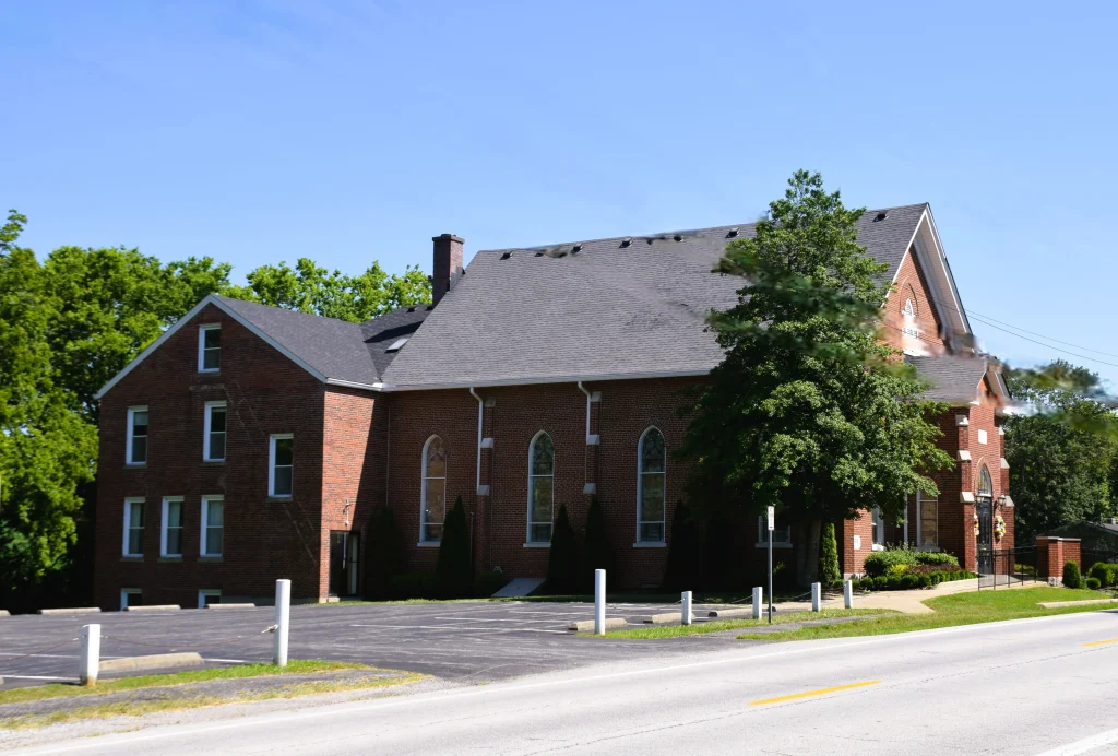 Brick church building in Finchville with tall pitched roof and arched windows