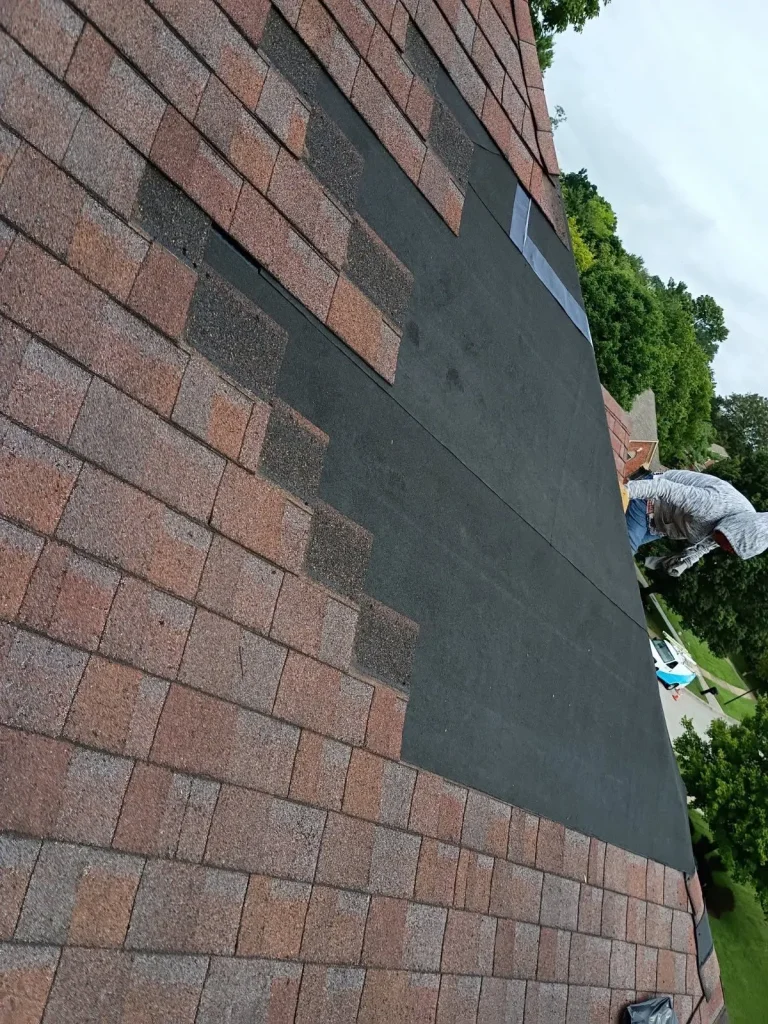 Partially repaired roof with damaged shingles on a Louisville home