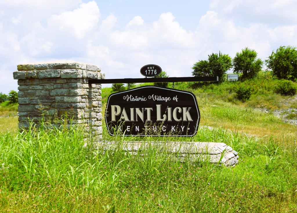 Paint Lick, Kentucky welcome sign surrounded by green grass and trees