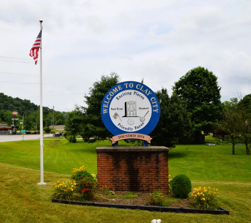 Welcome to Clay City sign with green lawn and American flag, ideal setting for clay city roofing services