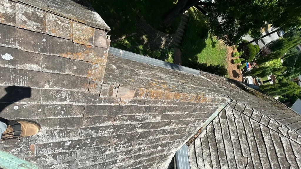 Cedar Shake Roof Damage on Louisville Home Aged cedar shake roof with lichen, cracked and missing shingles near the ridge, and metal valley flashing on a Louisville home.