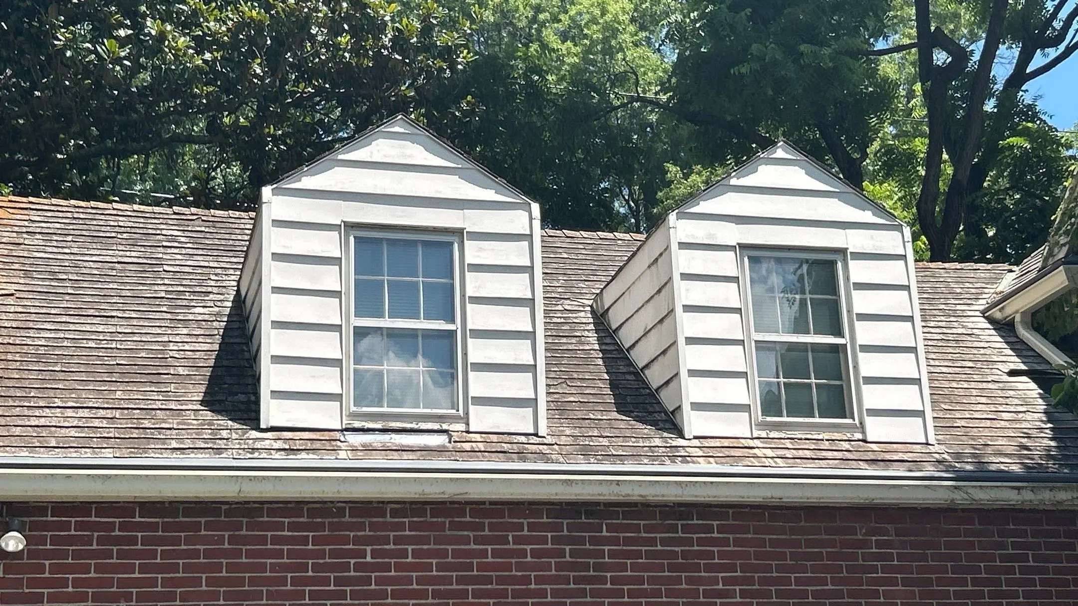 Louisville KY Dormer in Need of Repair Two dormer windows on a Louisville, KY home with an aging cedar shake roof and visible staining at the dormer bases, documented by AIC Roofing & Construction.