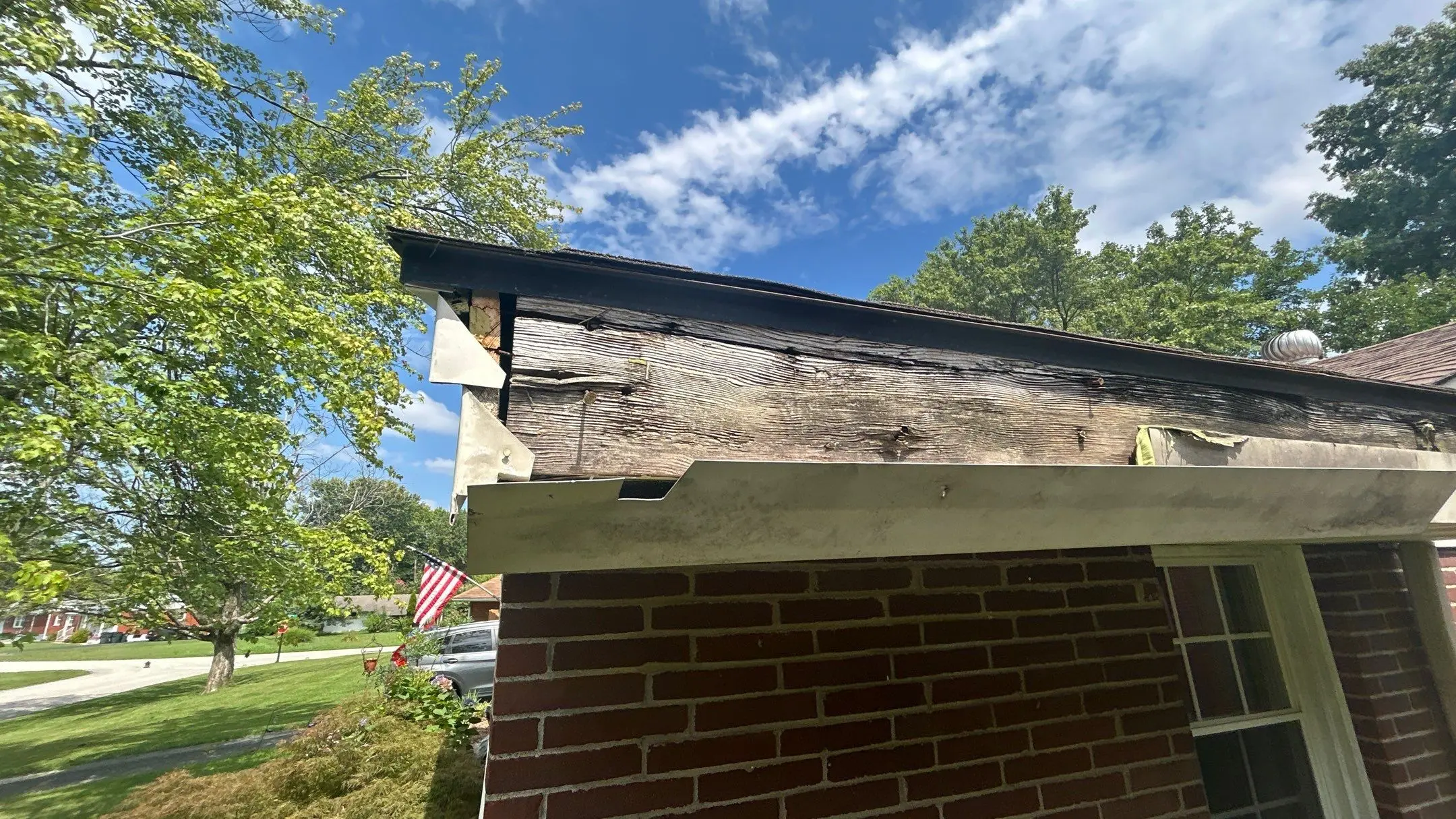 Louisville KY Fascia Damage – Before Gutter Replacement | AIC Roofing & Construction Rotted fascia and failing gutter along the roof eave of a Louisville, KY brick home, documented for repair by AIC Roofing & Construction.