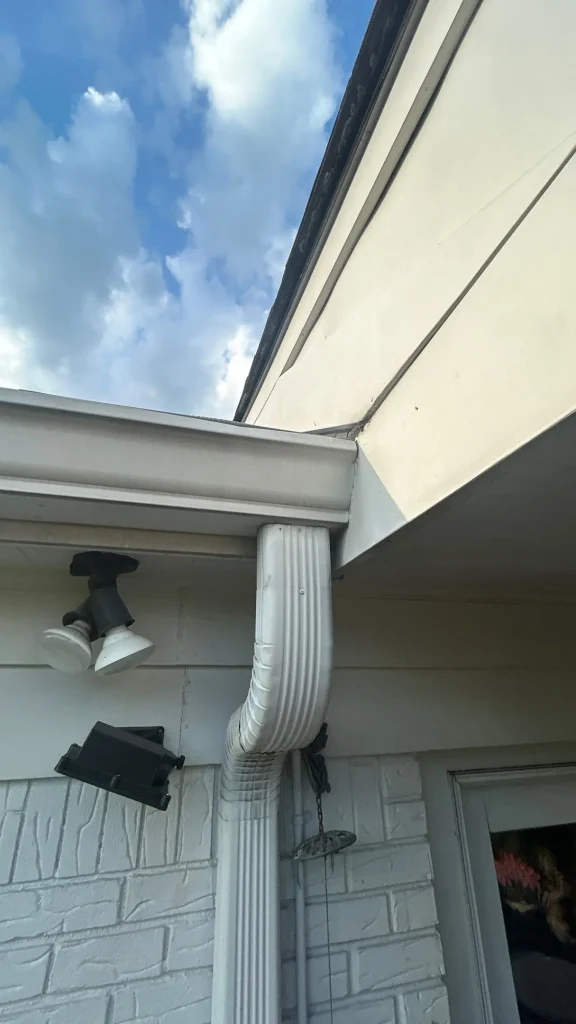 Close-up of a white K-style gutter and downspout at the roof eave of a Louisville, KY home, installed by AIC Roofing & Construction.