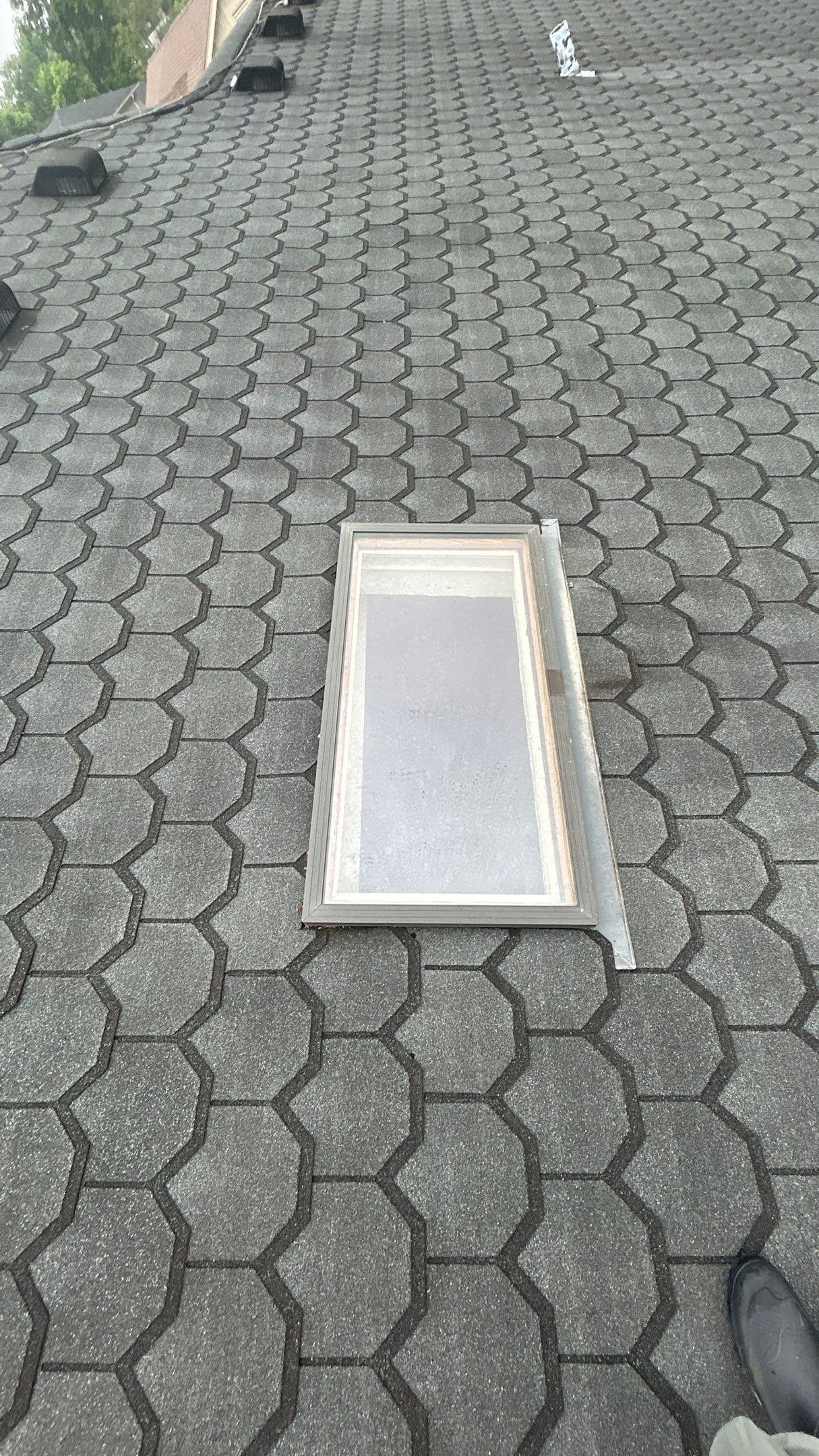 Skylight Repair on Louisville Home Skylight removed for repair on a Louisville home with metal flashing on gray hexagonal asphalt shingles.