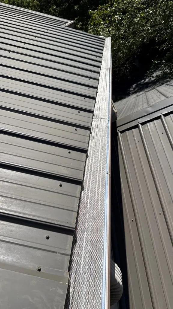 Gutter guards installed on a Louisville home with a gray metal roof, providing leaf protection and improved drainage.