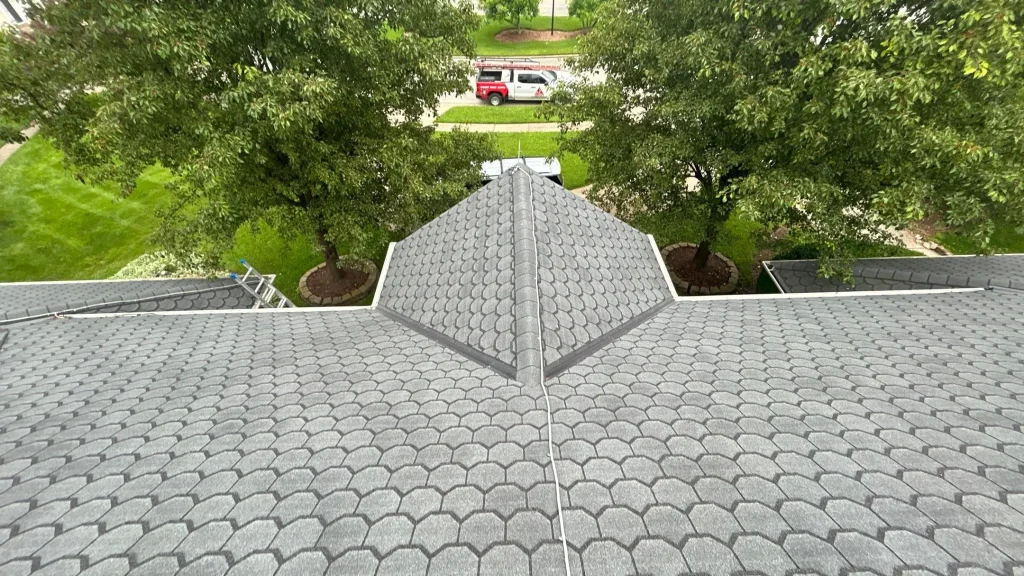 Louisville home roof with gray patterned shingles and ridge line, with a red contractor service truck visible in the background.