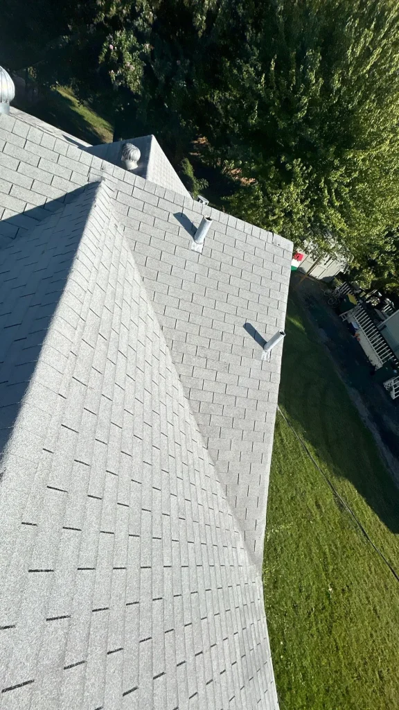 Louisville roof with light gray asphalt shingles, showing vent penetrations and ridge line in need of repair.