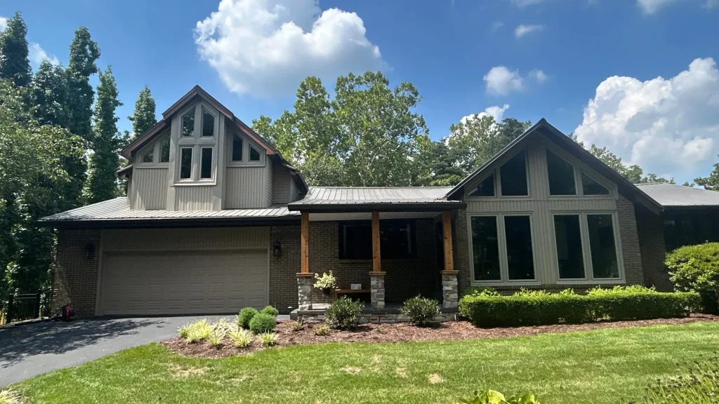 Louisville home with a new metal roof replacement, large windows, and a brick and siding exterior on a sunny day.