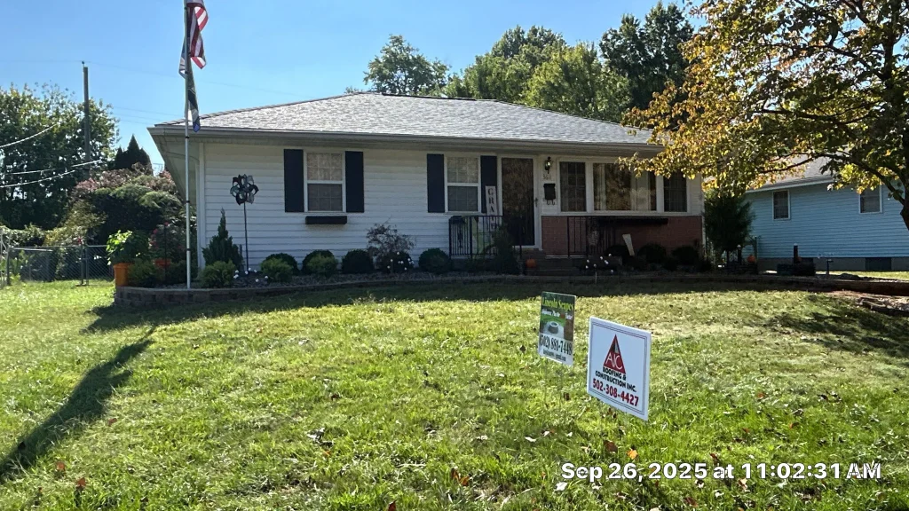 Louisville home after roof replacement with new asphalt shingles, white siding, and black shutters, with AIC sign in the yard.