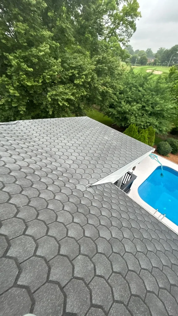 Louisville home roof with gray patterned shingles overlooking a backyard swimming pool and trees.