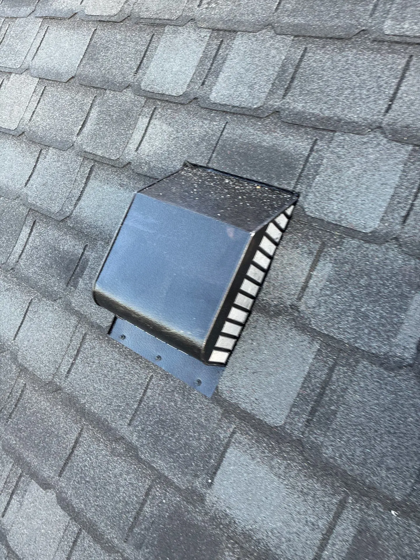 Close-up of a black roof vent penetration installed on gray asphalt shingles of a Louisville home.