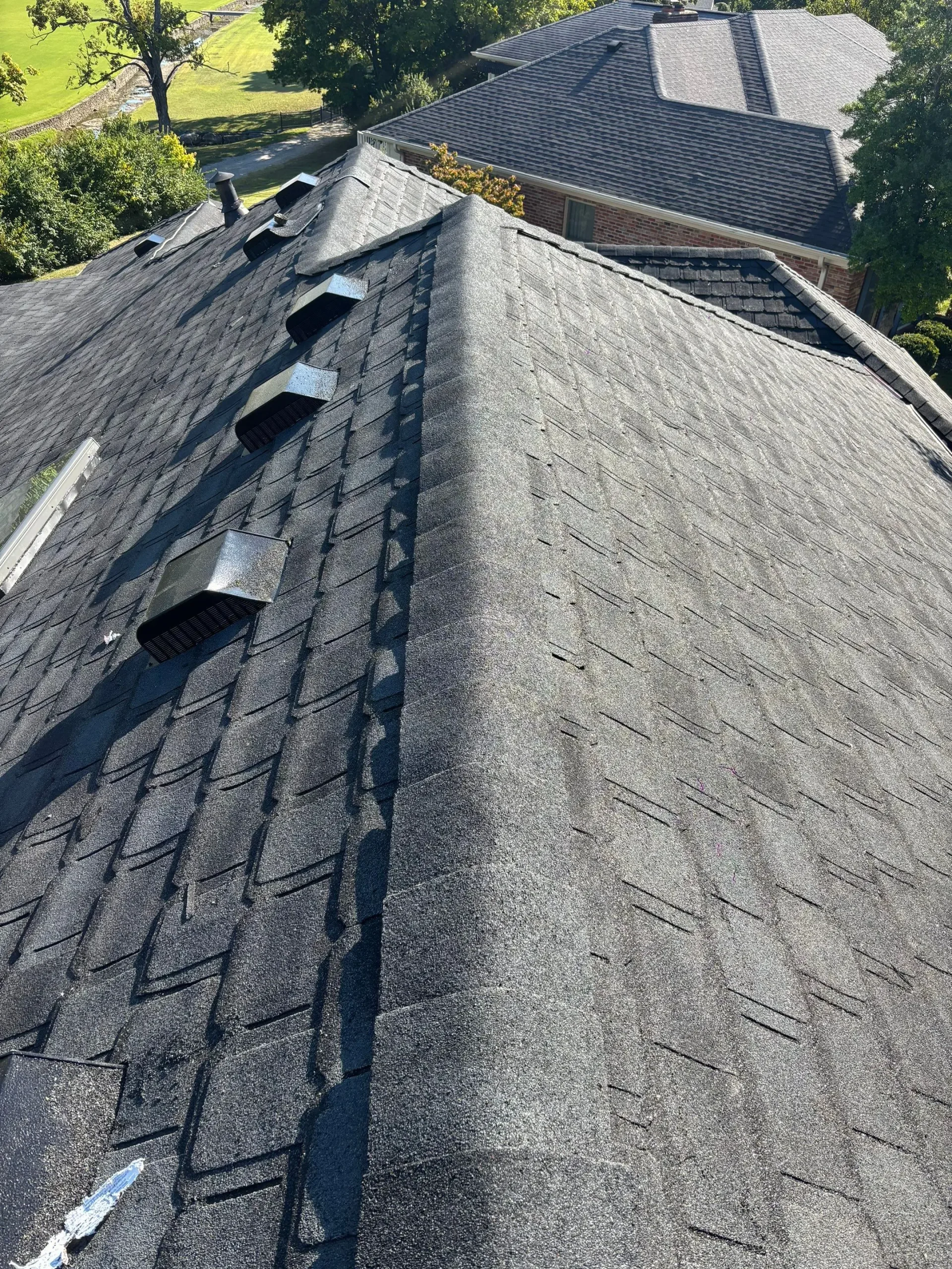 Louisville home roof ridge with multiple black ventilation penetrations installed across dark asphalt shingles.