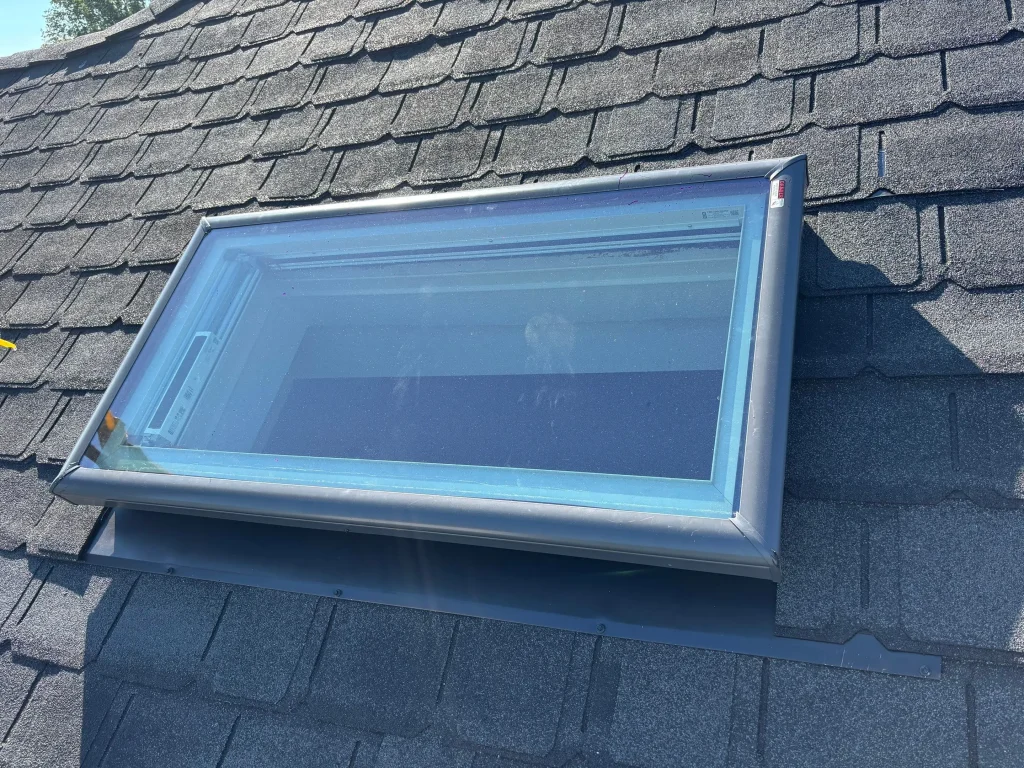Louisville roof skylight with surrounding asphalt shingles and visible metal flashing for waterproofing.