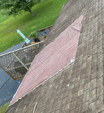 Tarp covering missing shingles on a Louisville roof after storm damage.
