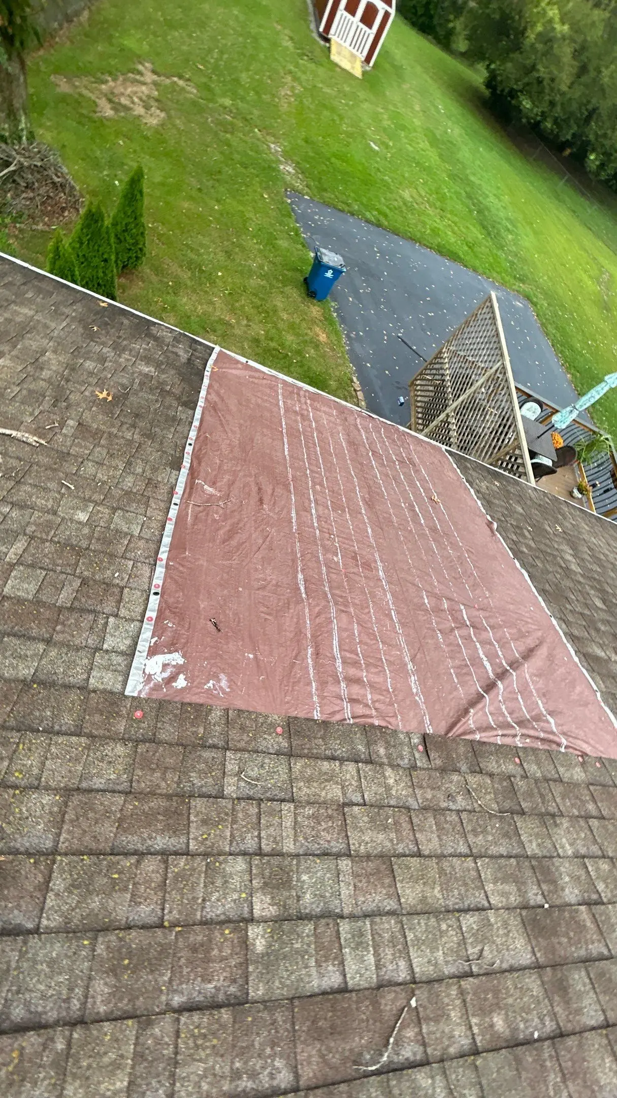 Simpsonville roof with missing shingles secured by tarp after storm damage.