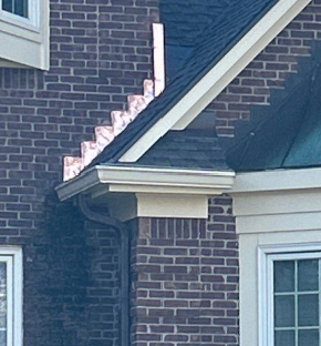 Close-up of copper step flashing and gutter detail on a brick home in Louisville, Kentucky, showing professional roof-to-wall transition work.