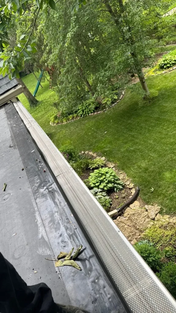 Close-up of newly installed aluminum gutter guards on a Louisville home surrounded by trees and landscaped yard, showing clean lines and debris protection.