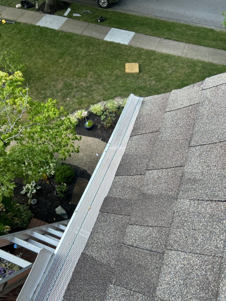Close-up view of newly installed aluminum gutter guards on a shingle roof of a Louisville home, showing a clean and secure fit along the roofline.