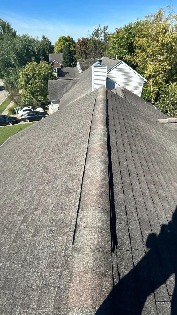 Newly installed asphalt shingle roof on a Louisville home under clear blue skies, showing ridge vent and clean alignment.