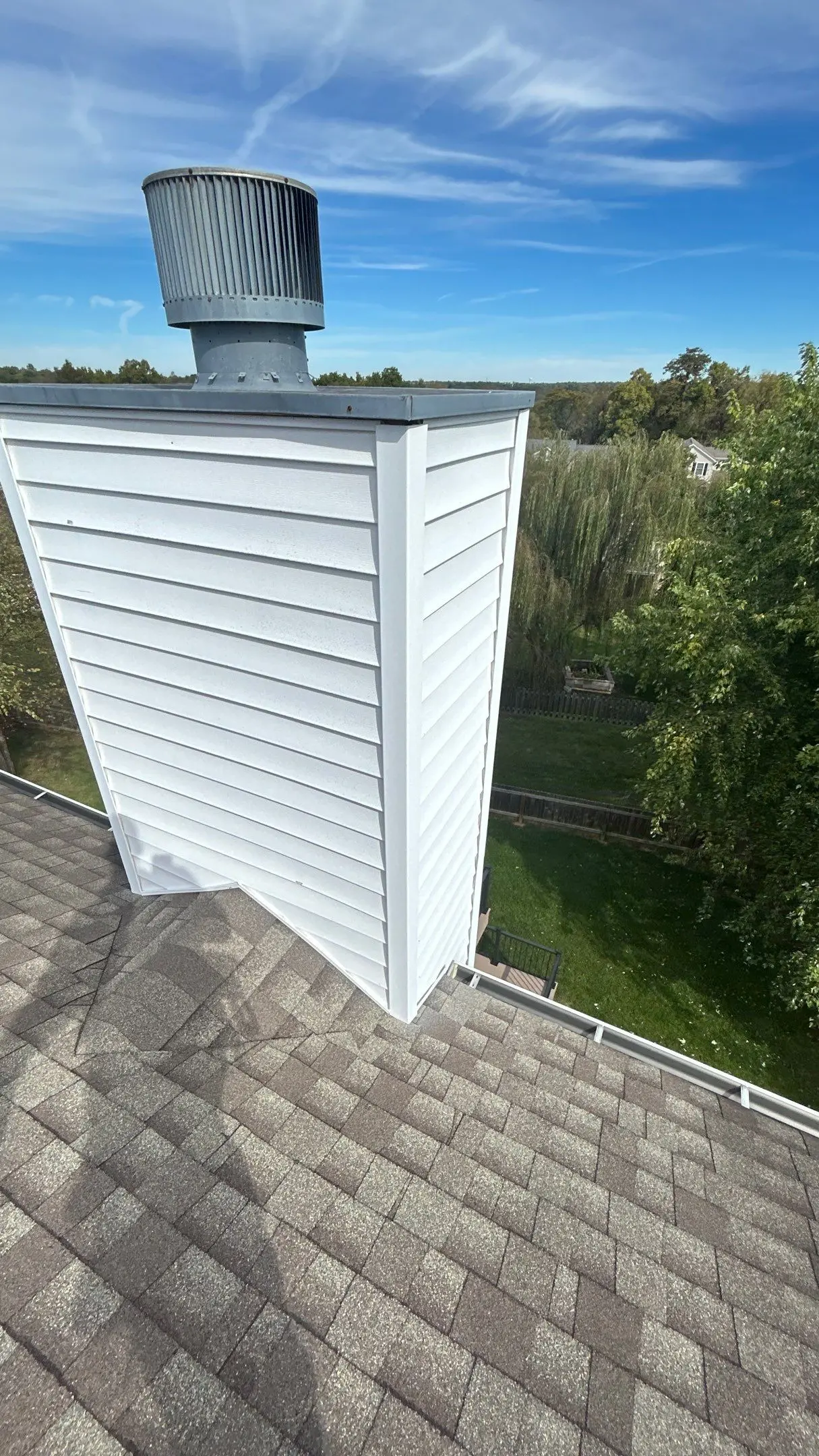 Chimney Flashing Inspection on Louisville Roof Close-up of a chimney with new siding and roof ventilation system on an asphalt shingle roof in Bardstown, Kentucky.