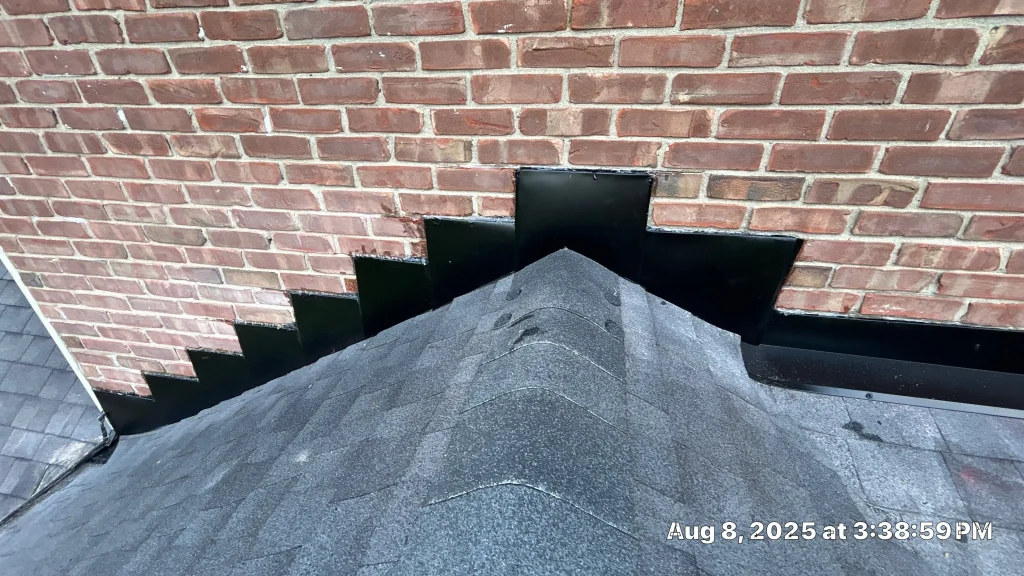 Step flashing installed along a brick wall above a new asphalt shingle roof in Bardstown, Kentucky.