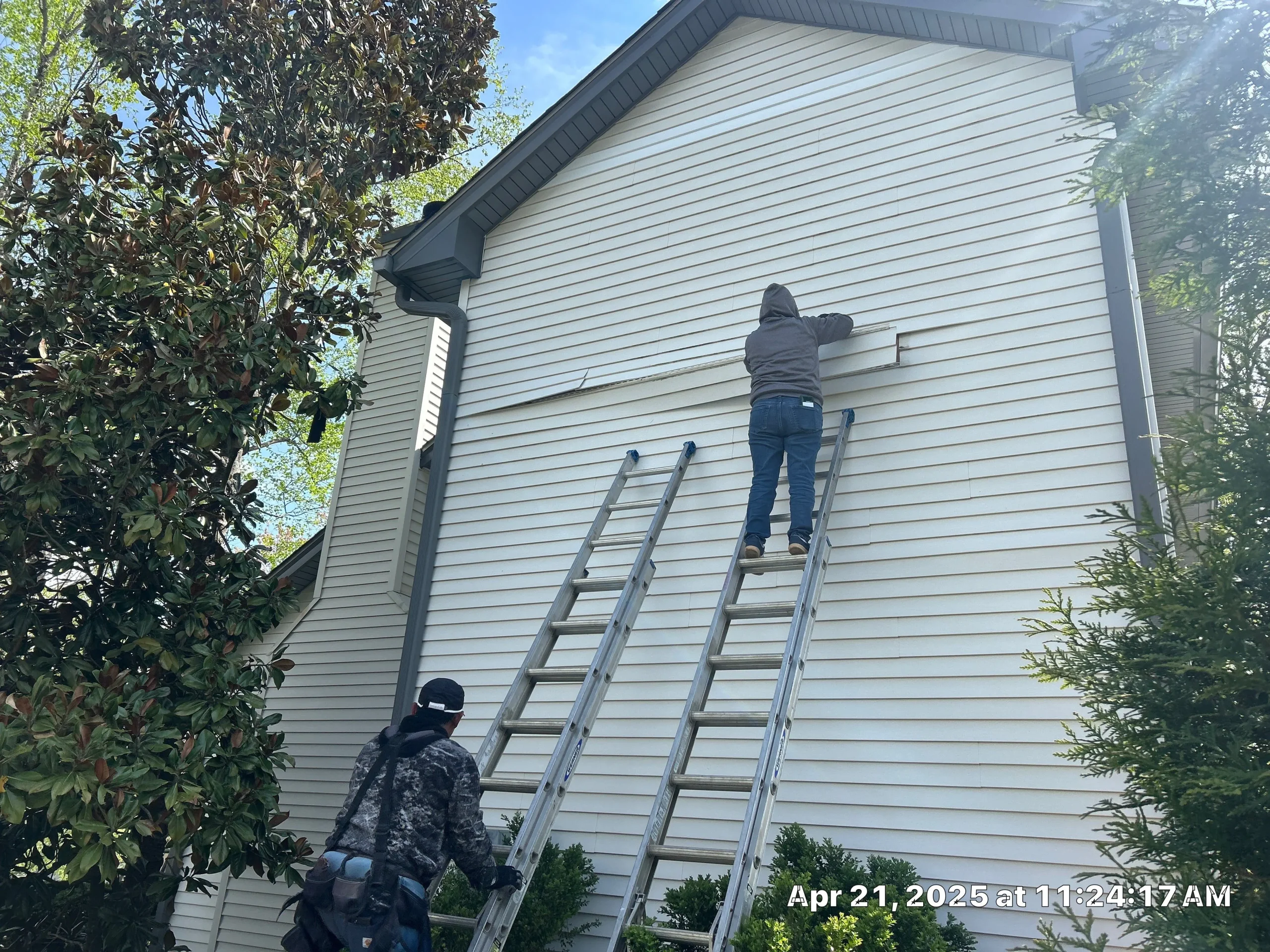 Contractors repairing vinyl siding on a Shelbyville, Kentucky home using ladders and professional tools.