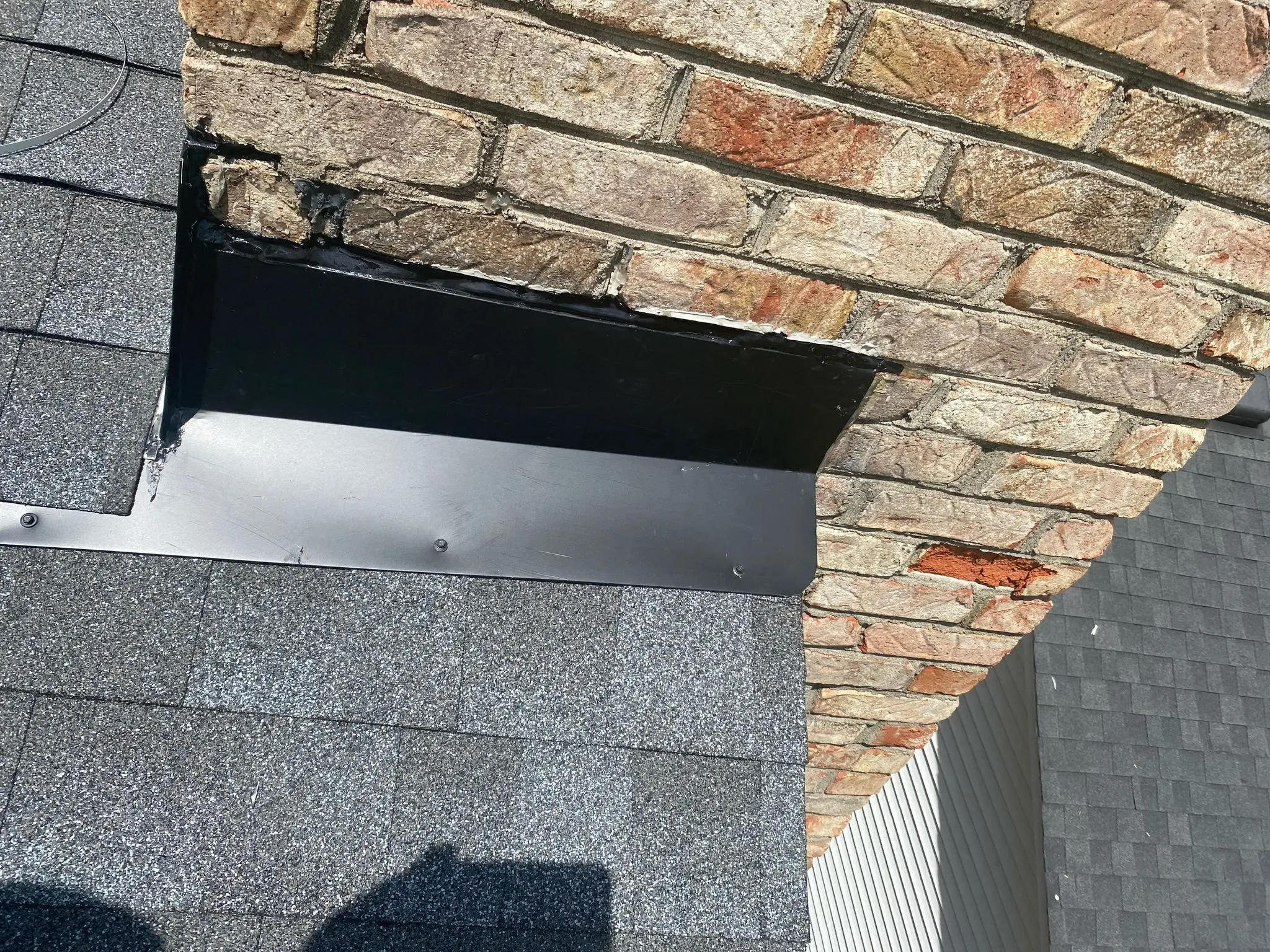 Damaged chimney flashing with worn sealant and gaps on a Louisville, KY shingle roof.