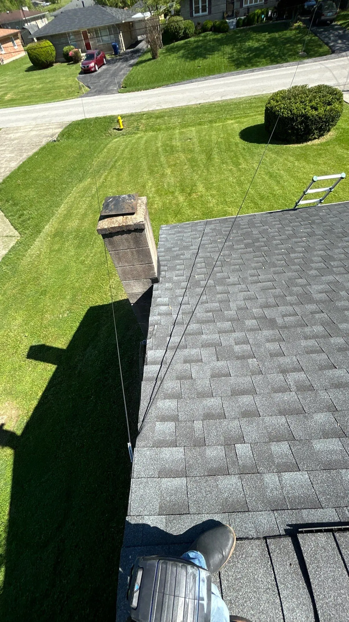 Leaning chimney in need of repair on a Louisville, KY home with a freshly mowed lawn in the background