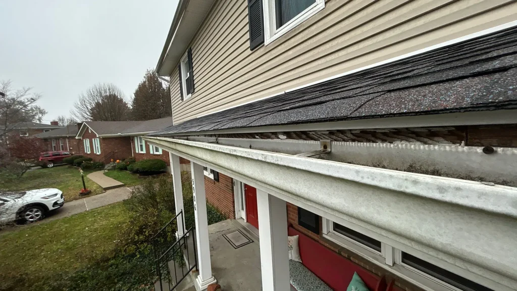 Old metal gutters pulling away from the roofline with visible fascia rot on a two-story Louisville KY home.