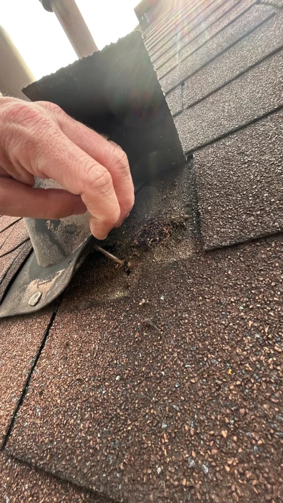 Shingle Repair in Progress on Louisville Roof Close-up view of damaged shingles and exposed nail beneath flashing on a Louisville, KY roof.